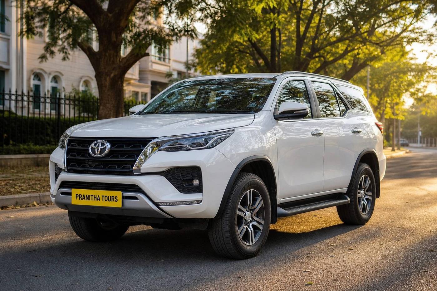 White SUV with Pranitha Tours yellow plate on a Bengaluru boulevard